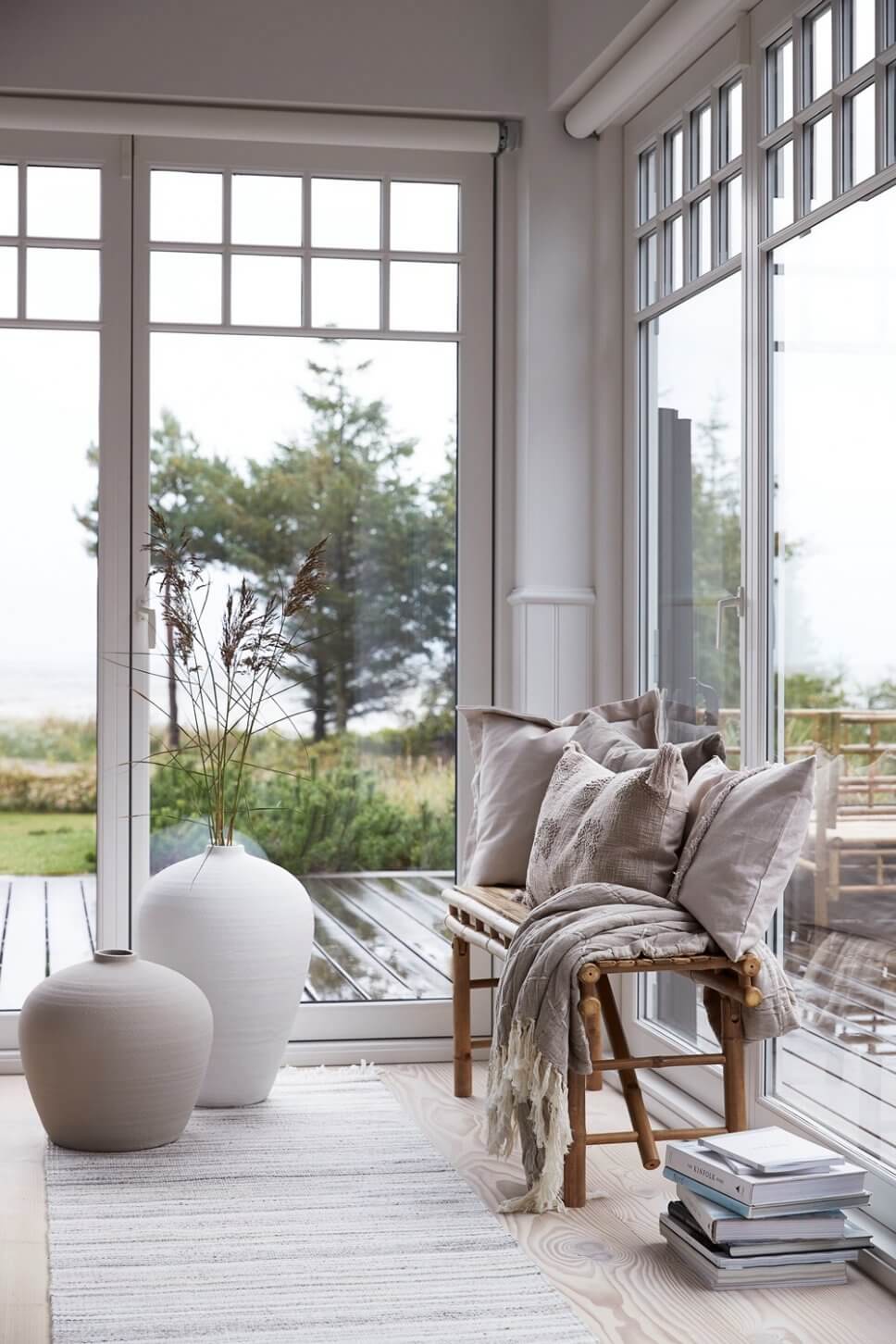 Bambusbank mit vielen Kissen vor Glastür zum Garten