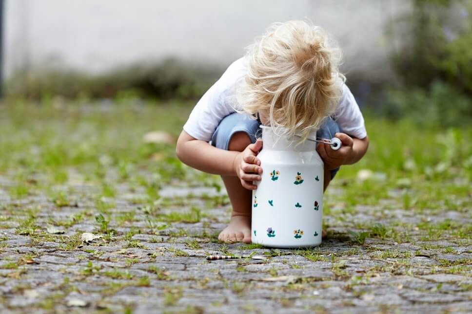 Blonder Junge schaut auf Kopfsteinpflaster im Milchkanne