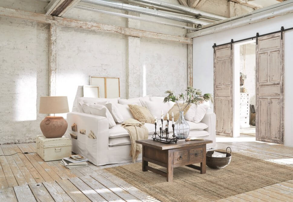 Weißes Hussensofa im Landhaus mit alten Holzschiebetüren