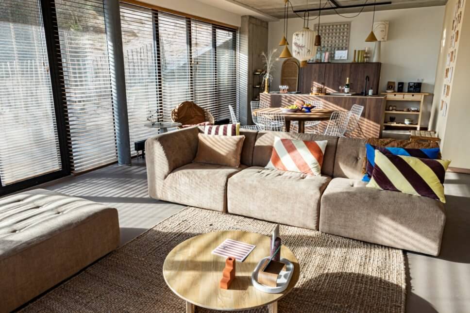 Modern eingerichteter Wohnraum mit Sofa und Essplatz sowie offener Küche im Hintergrund