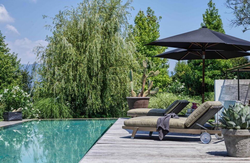 Modernes Sonnenliegen auf Terrasse neben Pool