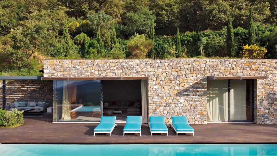 Moderne Sonnenliegen auf Terrasse neben Pool