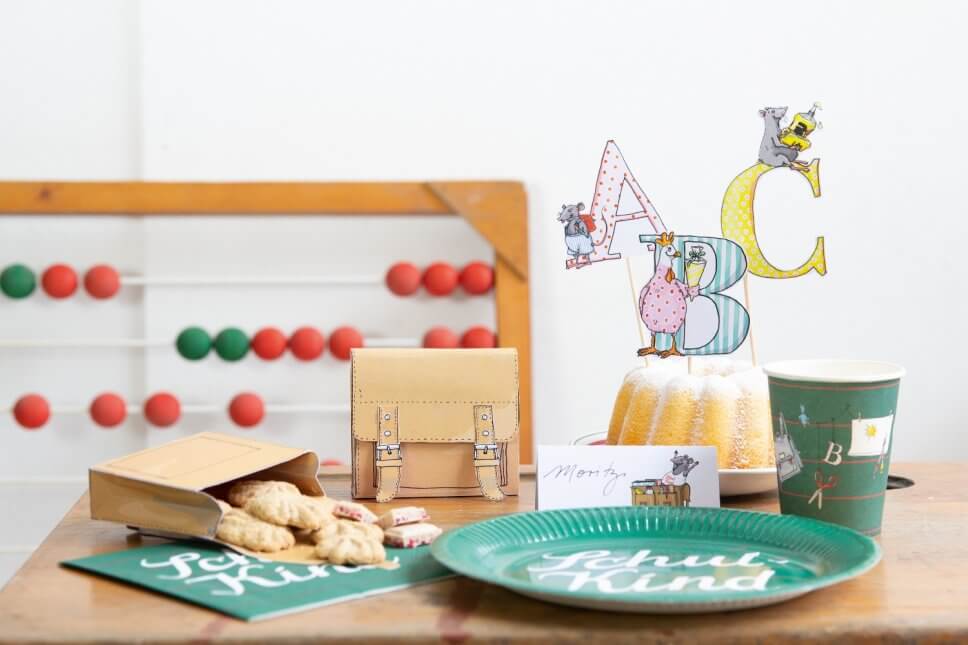 Kuchen, kleine Papierschulranzen mit Keksen gefüllt auf Tisch