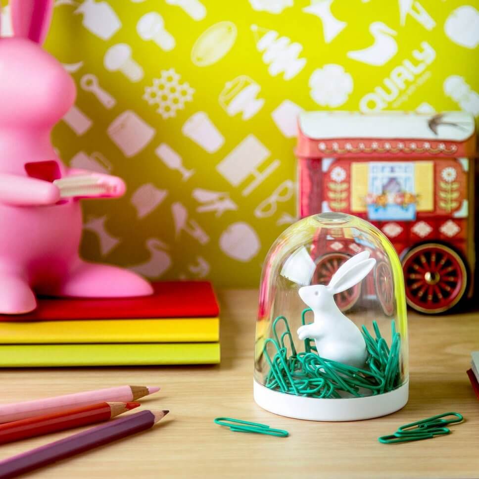 Hase im Glas voller Büroklammern, bunte Notizhefte und Stifte