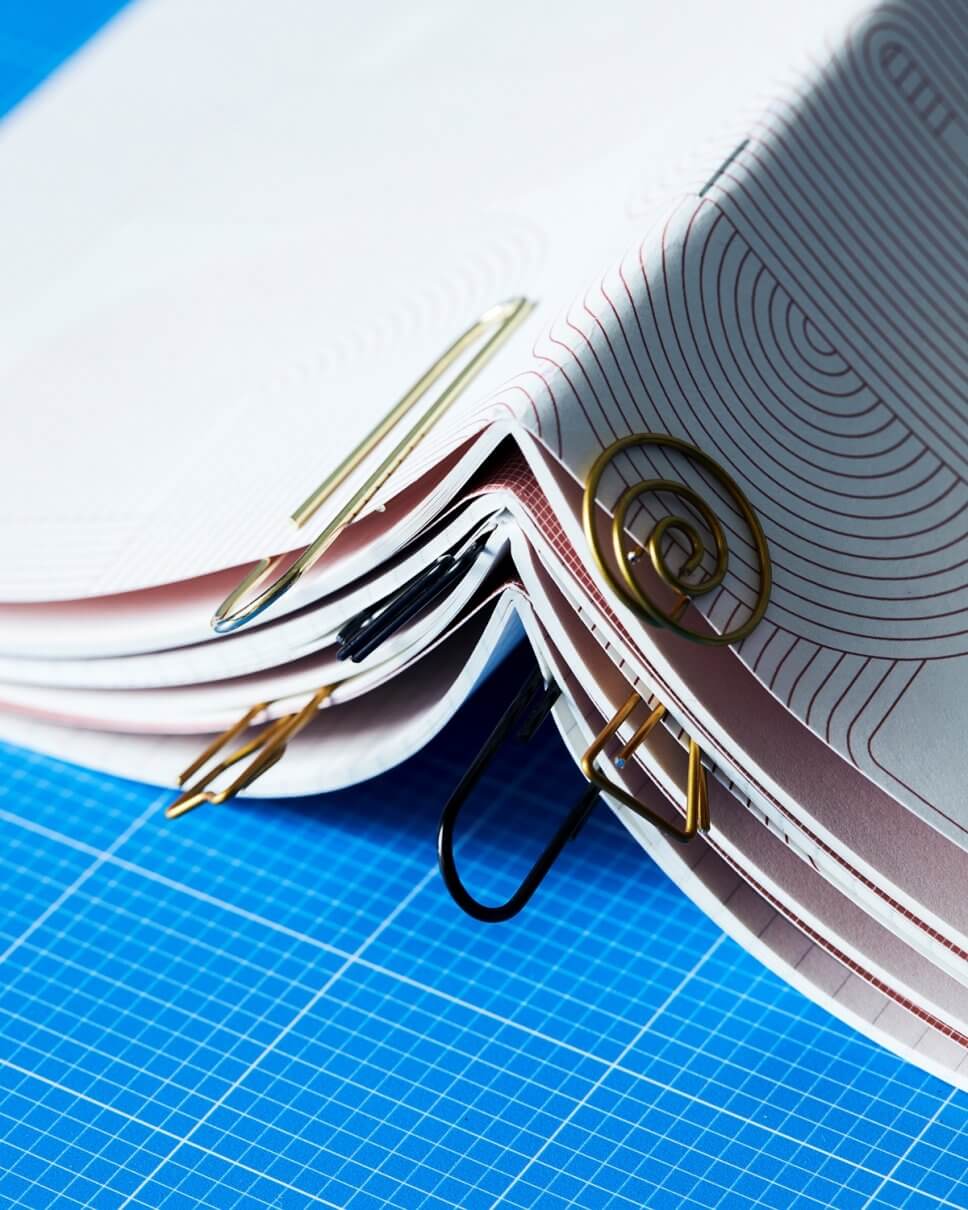 Verschewiden geformtte Büroklammern klemmen an mehreren übereinander gestapelten Heften