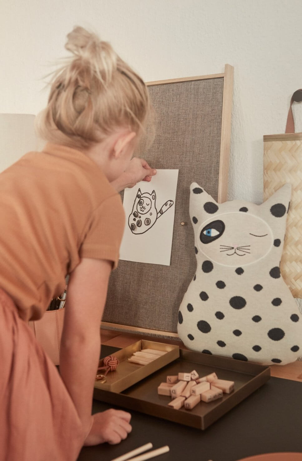 Mädchen pinnt an Schreibtisch ein Bild an eine Pinnwand