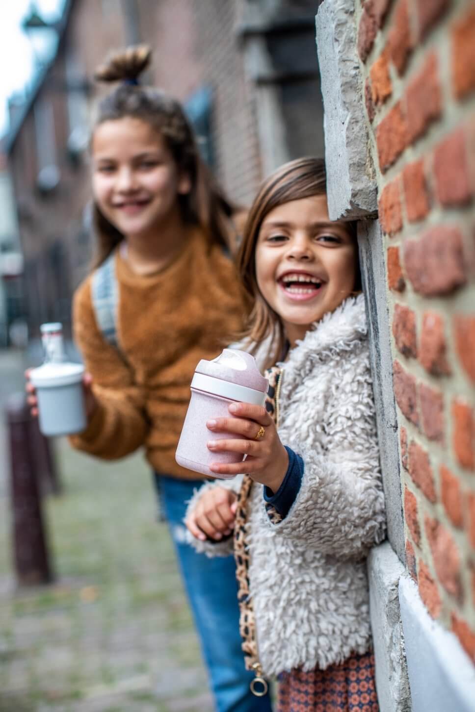 Zwei Mädchen stehen mit Trinklflaschen im Hauseingang