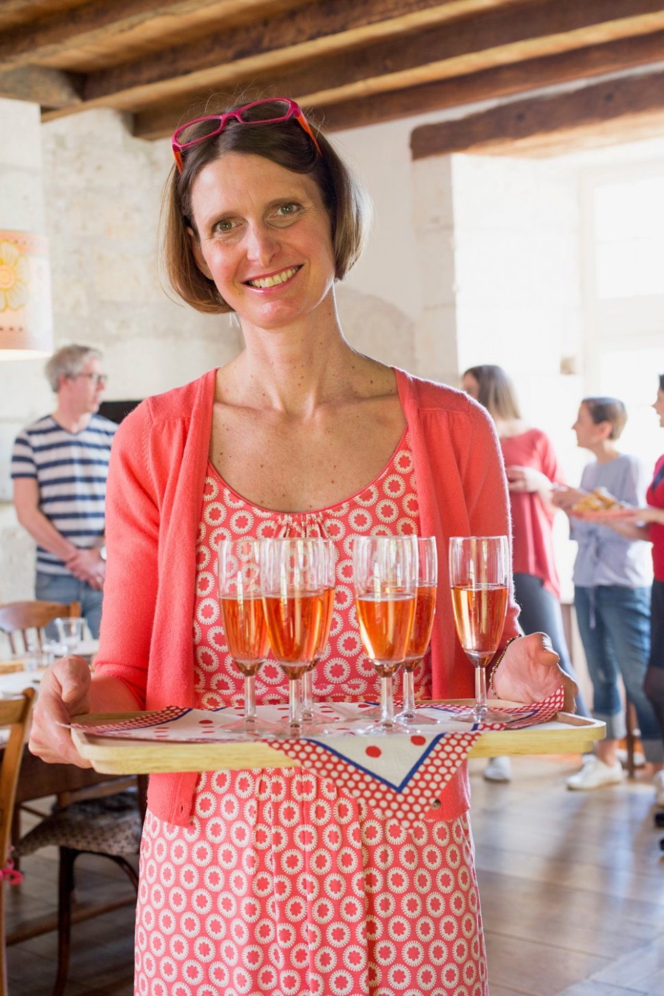 Frau trägt Tablett mit gefüllten Champagnergläsern in altem französischen Landhaus