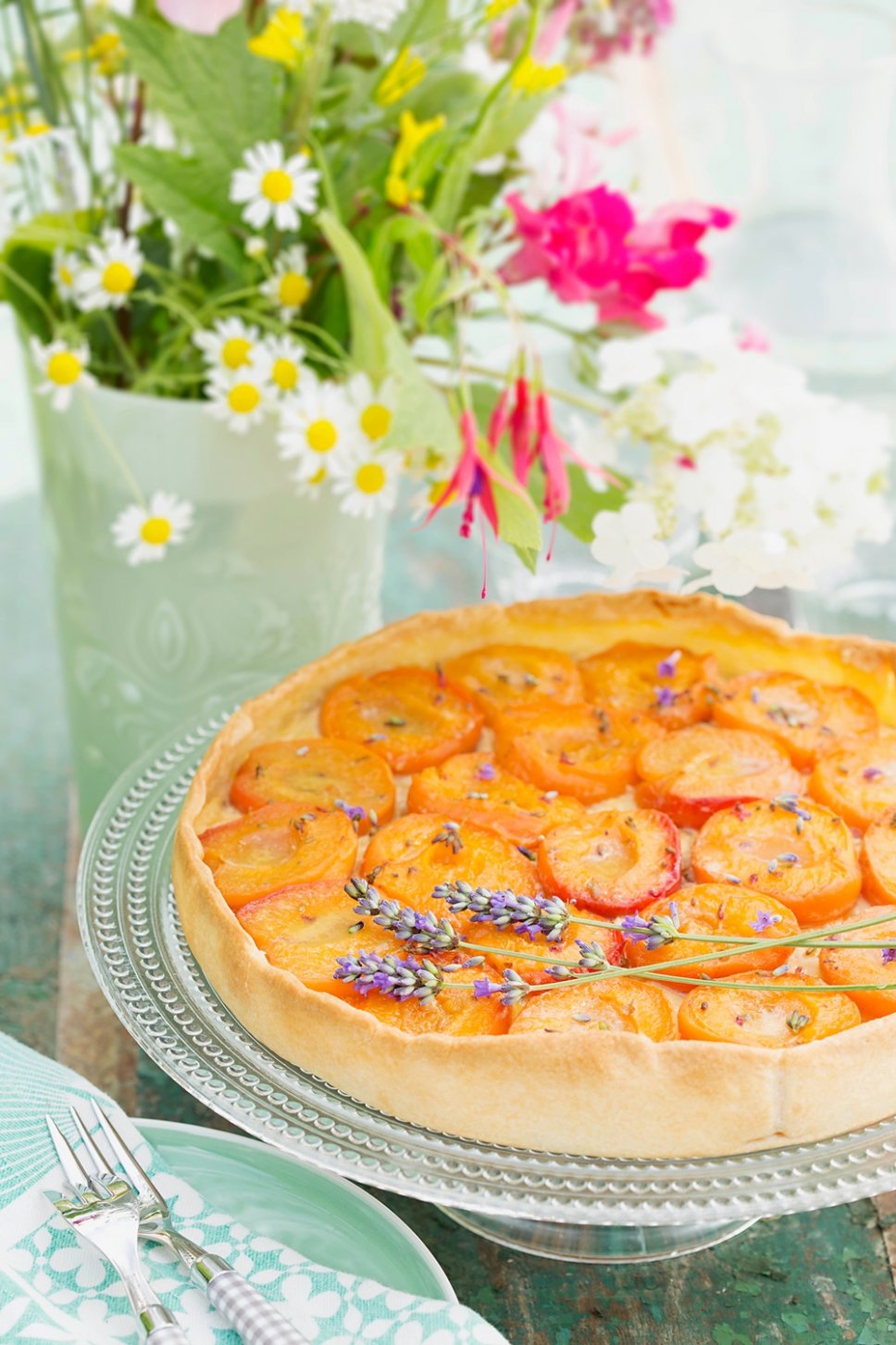 Pfirsichtarte und Wiesenblumen auf grünem Tisch