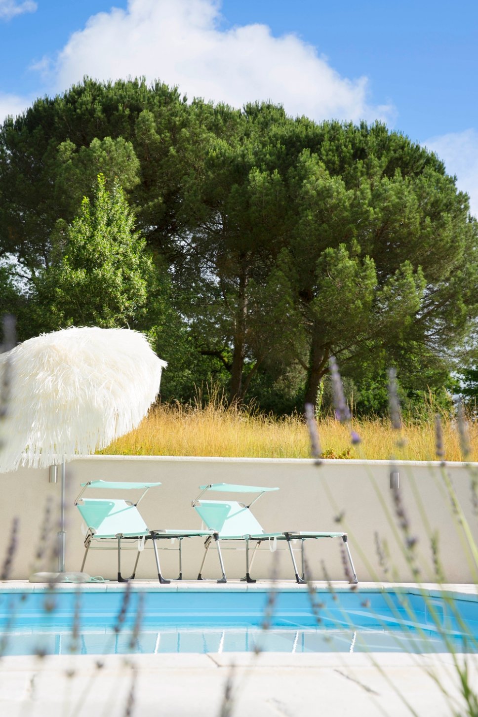 Liegestühle und Schirm vor Swimming Pool