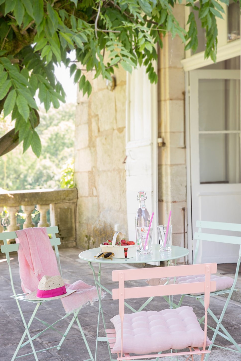 Farbenfroher Bistrotisch und Stühle auf Terrasse in altem französischen Landhaus