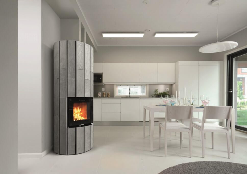 Modern eingerichtete offene Küche mit Kaminofen im Mittelpunkt