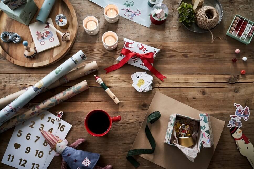 Tisch mit Papier, Kerzen udn kleinen Geschenken zum Basteln eines Adventskalenders