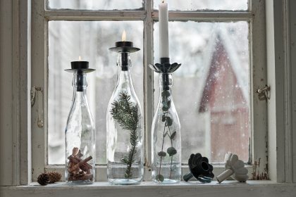 Glasflaschen als Kerzenhalter auf Fensterbrett im schwedischen Landhausstil