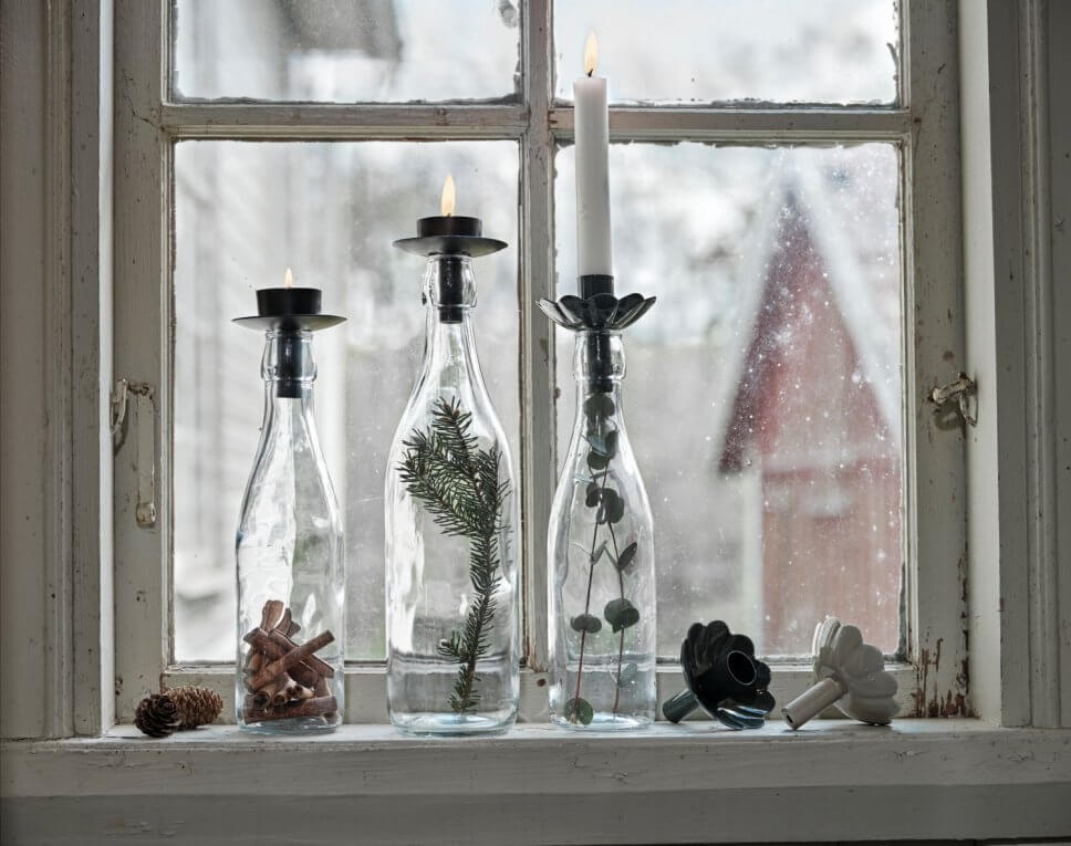 Glasflaschen als Kerzenhalter auf Fensterbrett im schwedischen Landhausstil