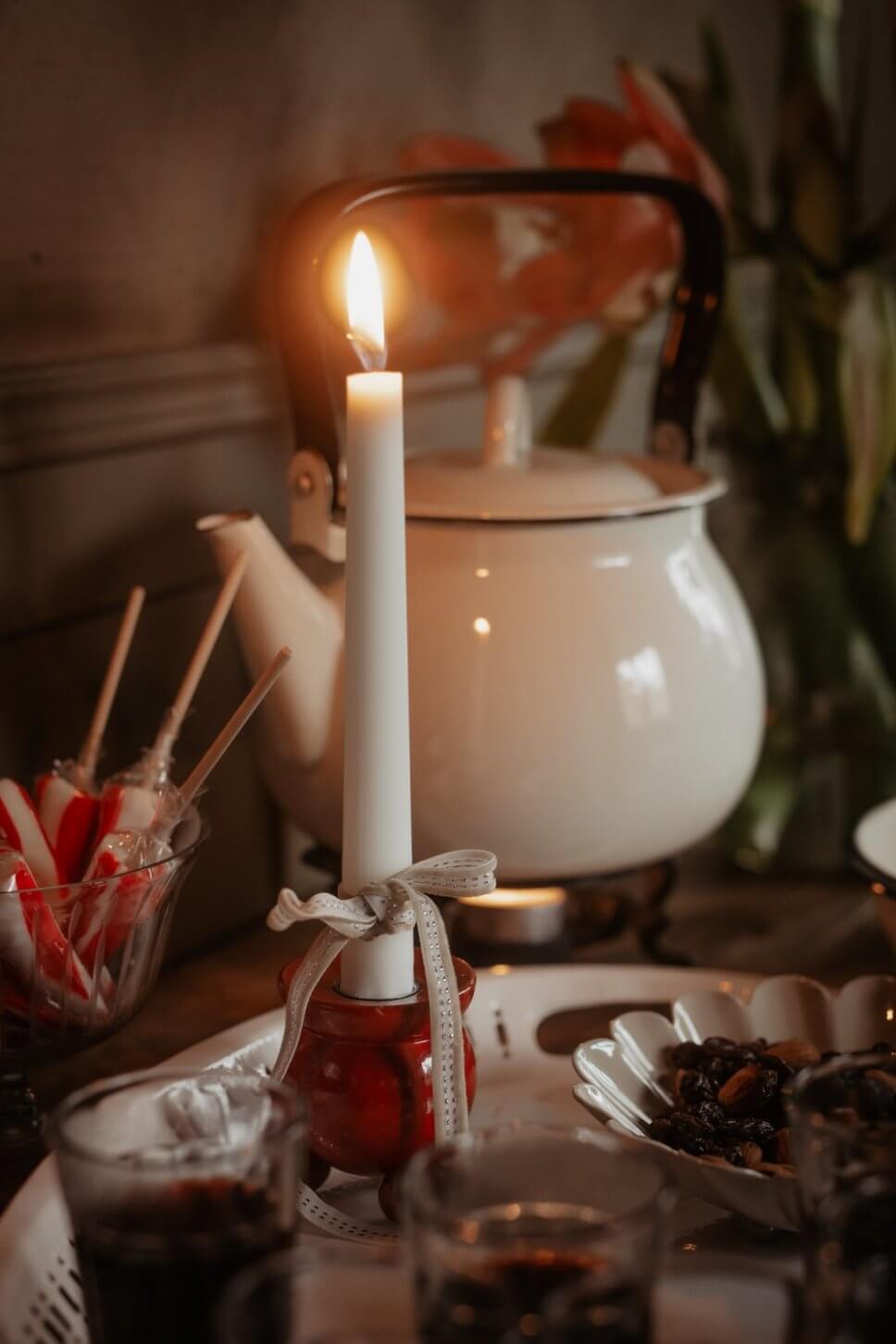 Brennende Kerze im mit Weihnachtsdeko geschmückten Zimmer im Altbau