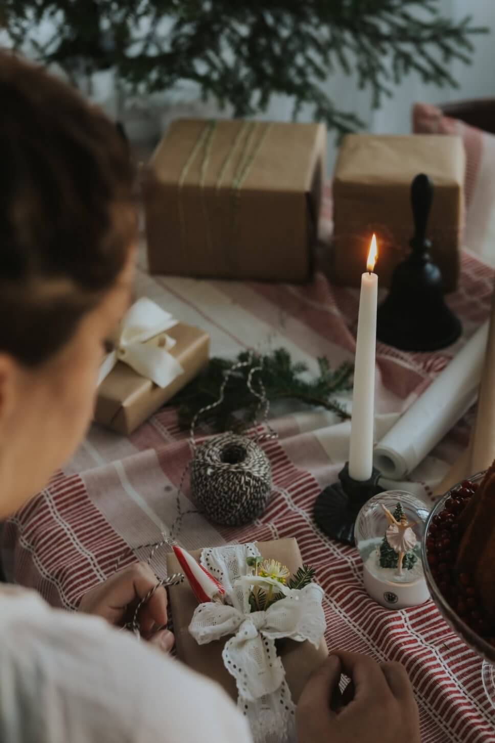 Frau packt Weihnachtsgeschenke auf Kaffetafel mit Weihnachtsdeko geschmückt