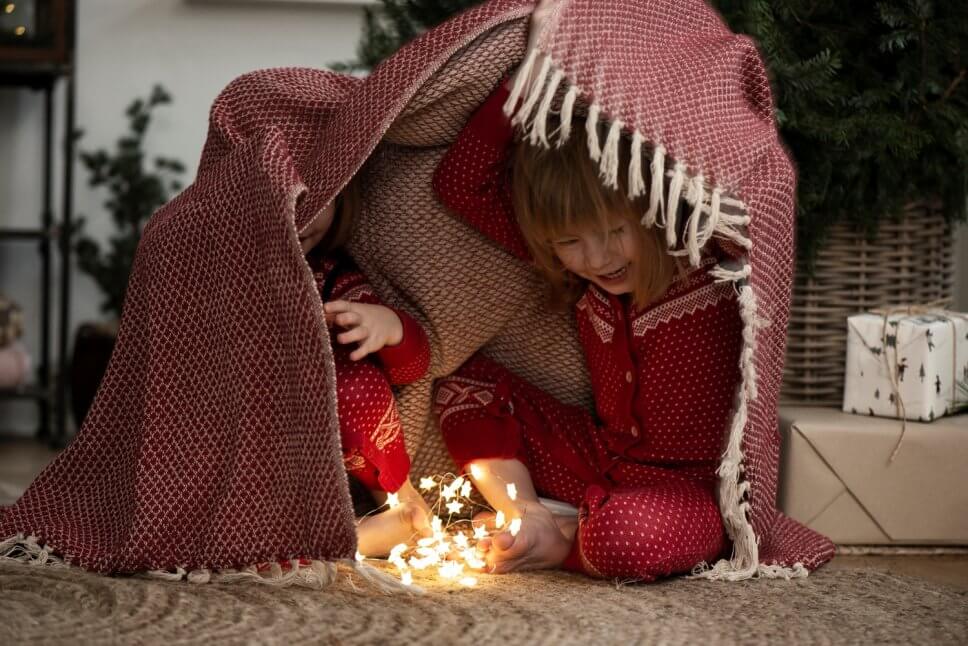 Zwei Kinder verstecken sich unter einer Wolldecke