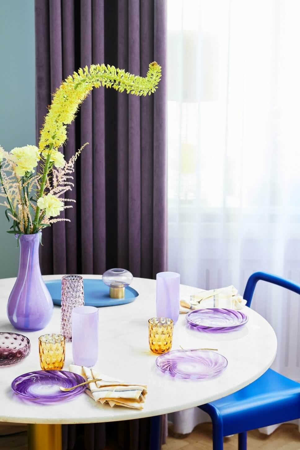 Mit lila und bernsteinfarbenen Gläsern und Glastellern gedeckter Tisch