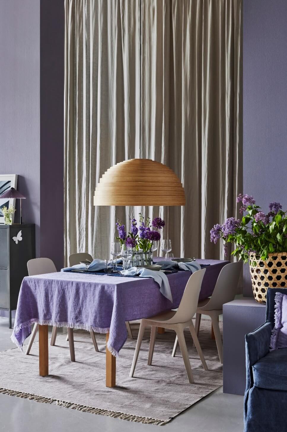 Modern eingerichtetes Esszimmer mit lila Tischdecke und lila Blumen