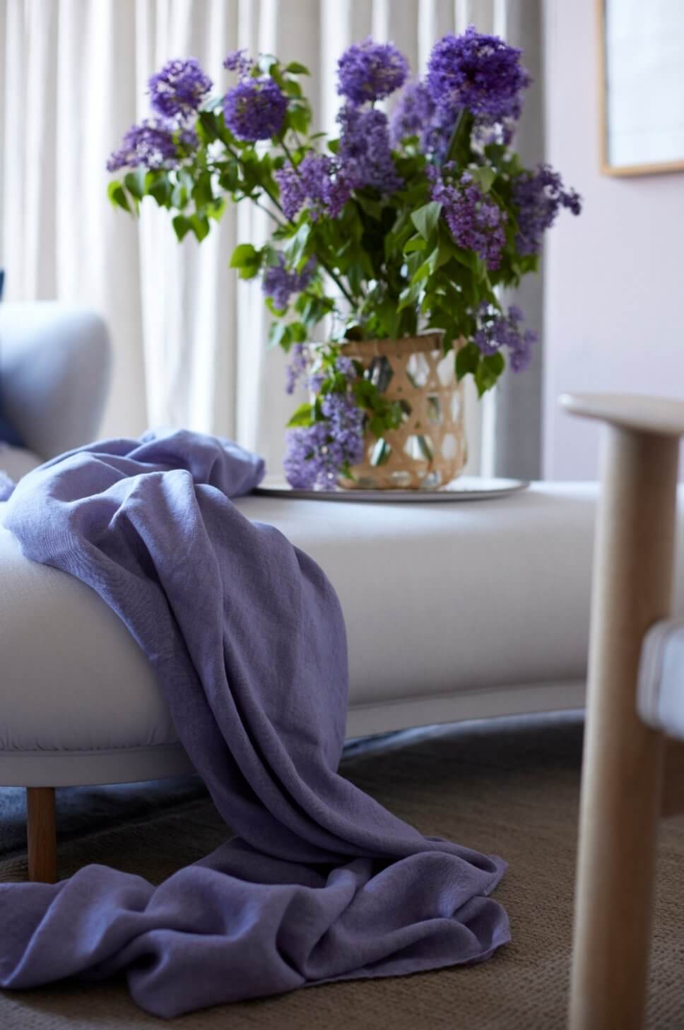 Modern eingerichtetes Wohnzimmer mit grauem Sofa und lila Wolldecke darauf