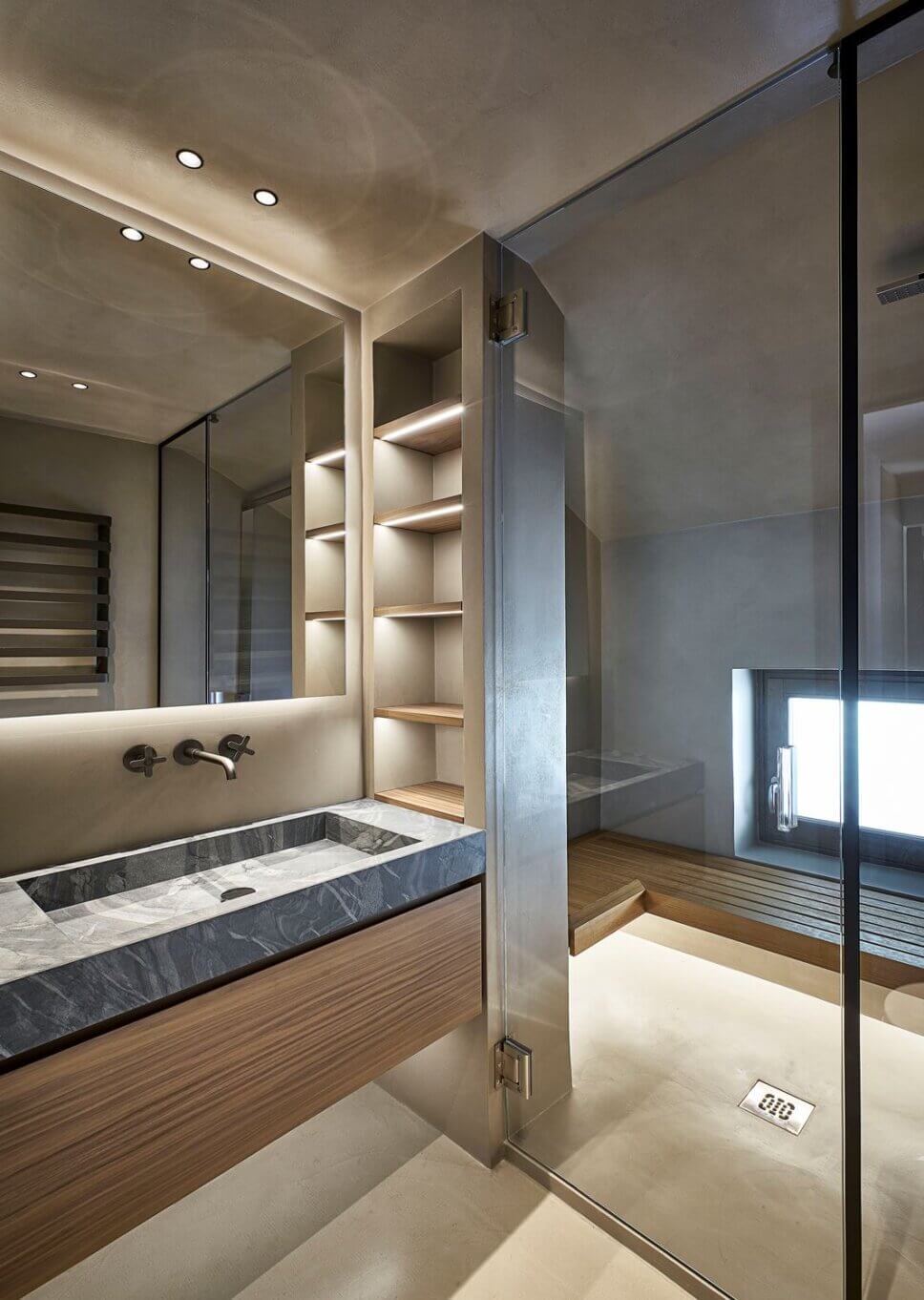 Minimalistisch eingerichtetes Badezimmer mit Waschtisch aus Stein und Einbauten aus Holz