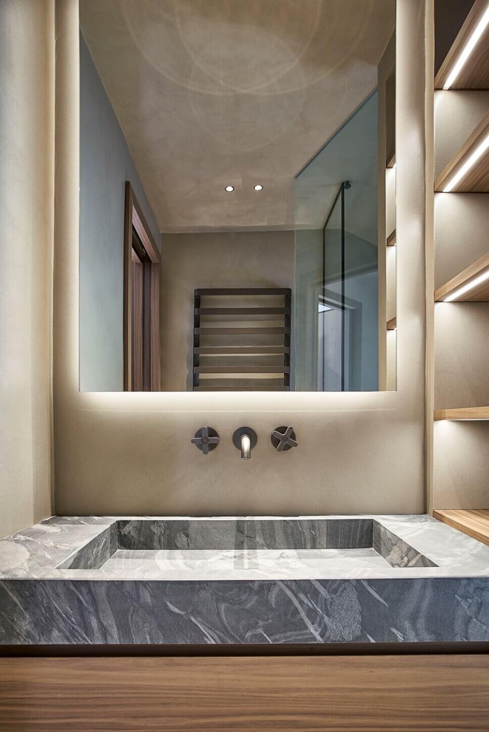 Minimalistisch eingerichtetes Badezimmer mit Waschtisch aus Stein und Einbauten aus Holz