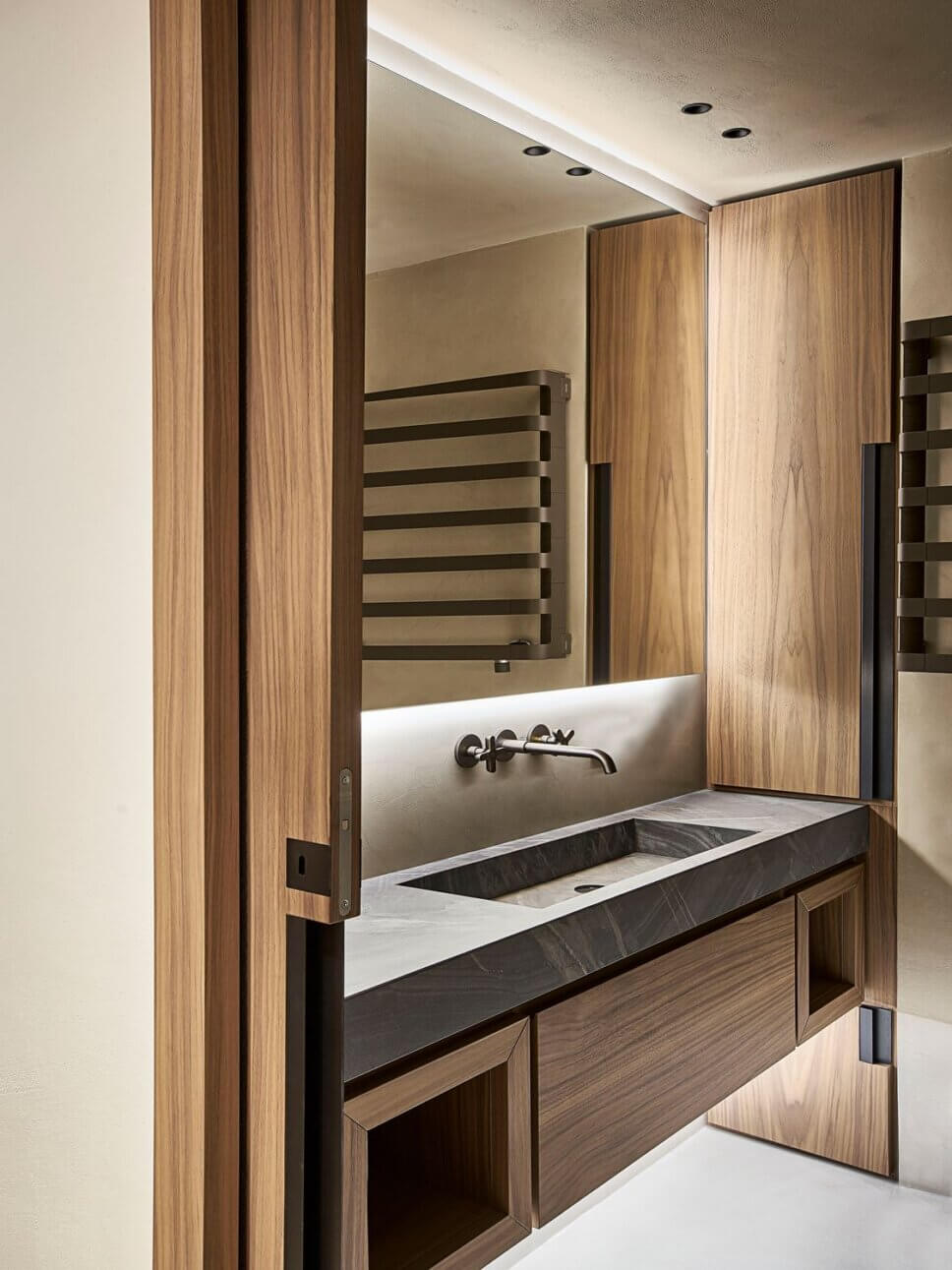 Minimalistisch eingerichtetes Badezimmer mit Waschtisch aus Stein und Einbauten aus Holz