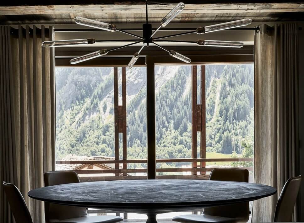 Minimalistisch eingerichteter offener Wohnraum mit Esstisch und Stühlen im modernen Chalet-Stil