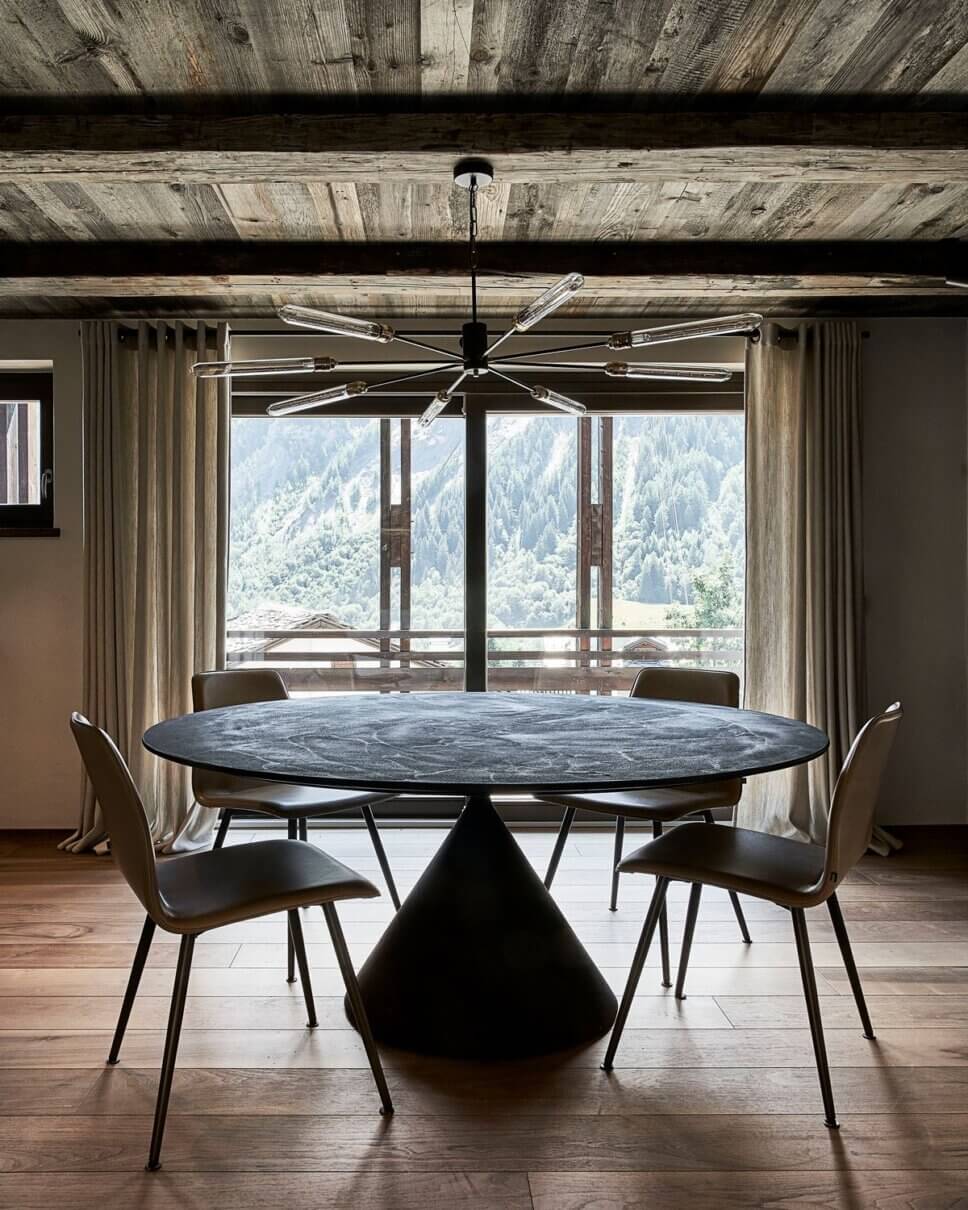 Minimalistisch eingerichteter offener Wohnraum mit Esstisch und Stühlen im modernen Chalet-Stil