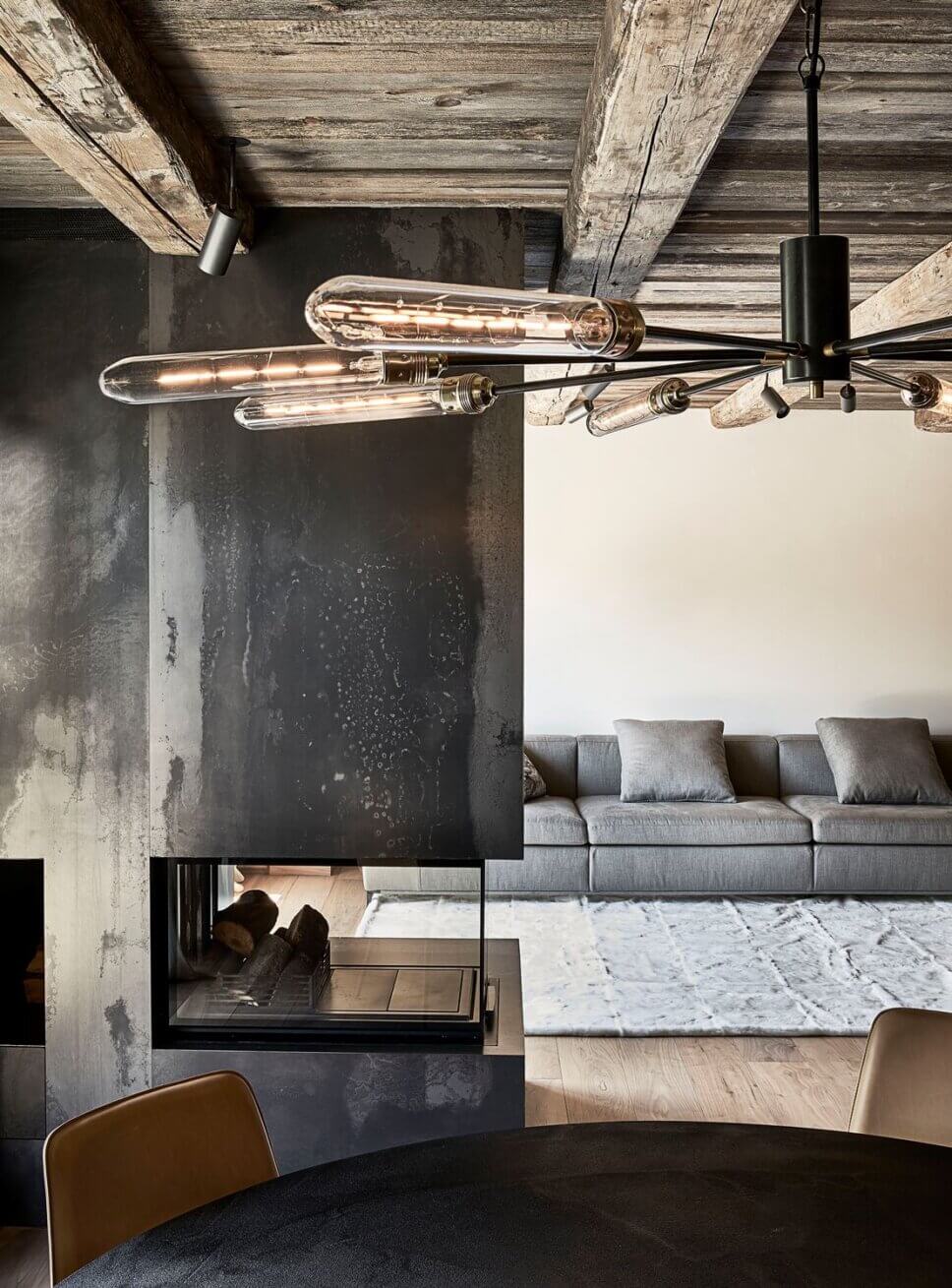 Minimalistisch eingerichteter offener Wohnraum mit Kamin und Sofa im modernen Chalet-Stil