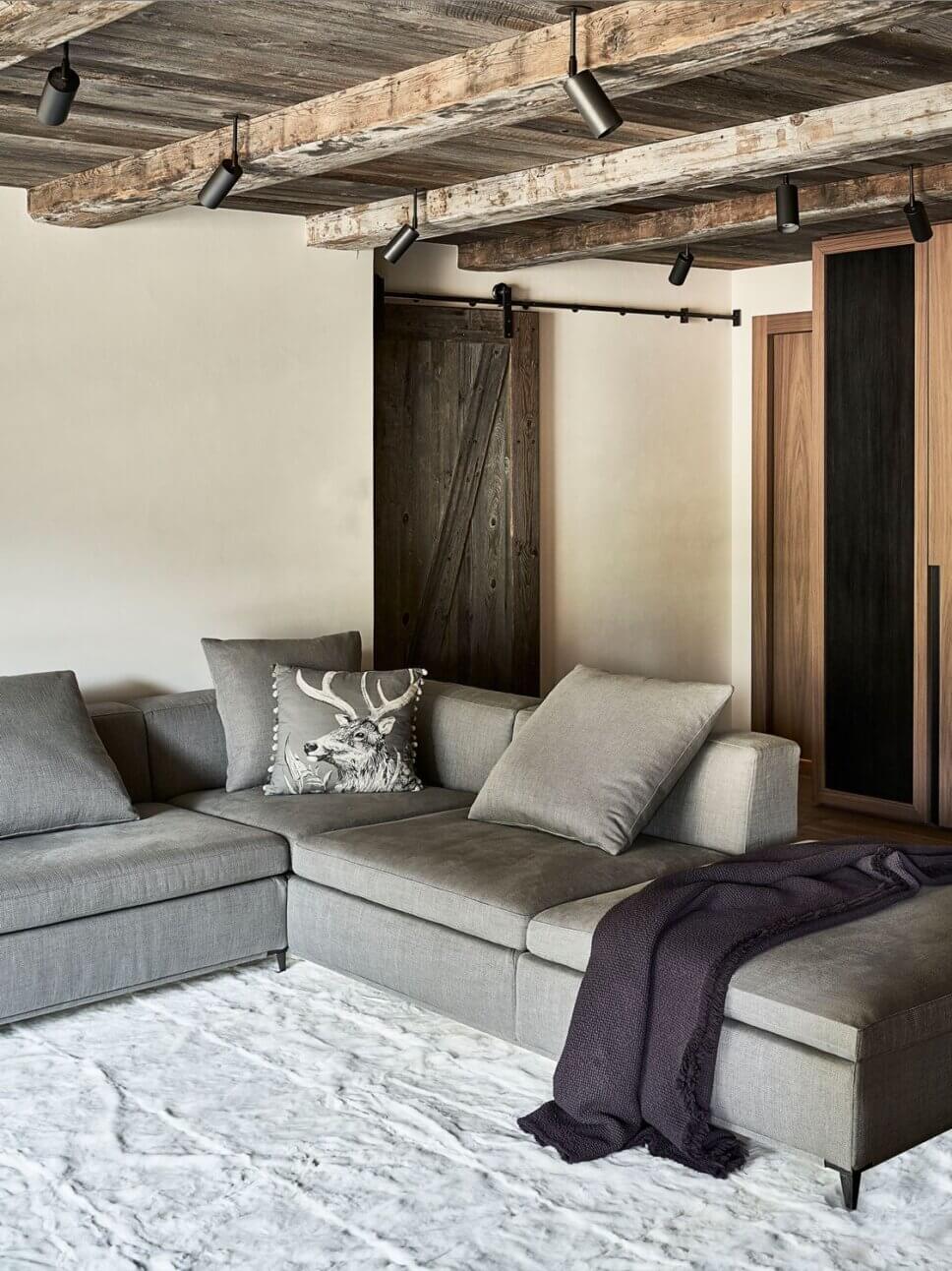 Minimalistisch eingerichteter offener Wohnraum mit Sofa im modernen Chalet-Stil