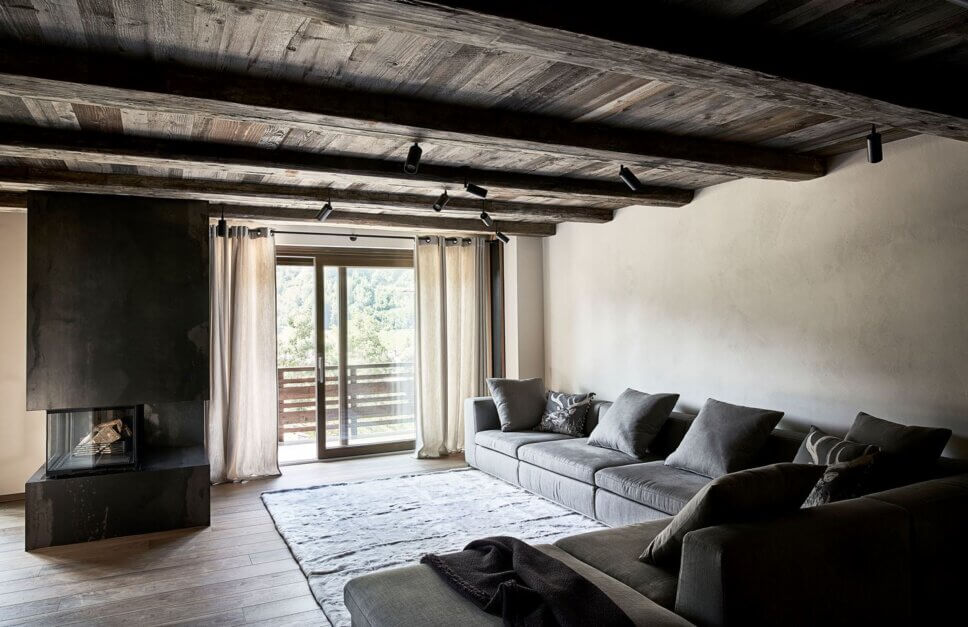 Minimalistisch eingerichteter offener Wohnraum mit Kamin und Sofa im modernen Chalet-Stil