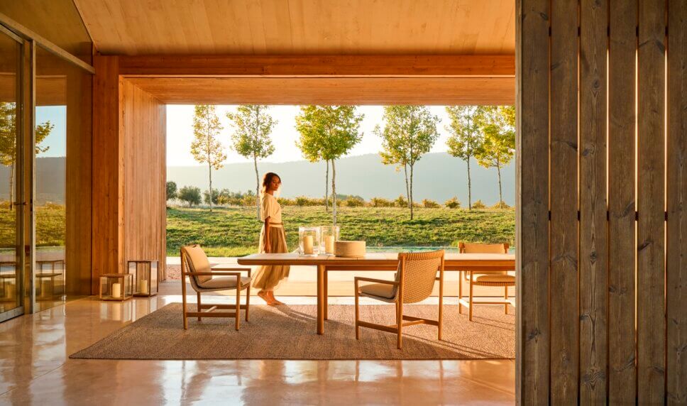 Frau steht zwischen modernen Gartenmöbeln auf der Terrasse