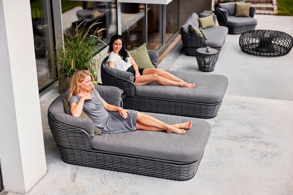 Zwei Frauen liegen auf modernen Sonnenliegen auf der Terrasse