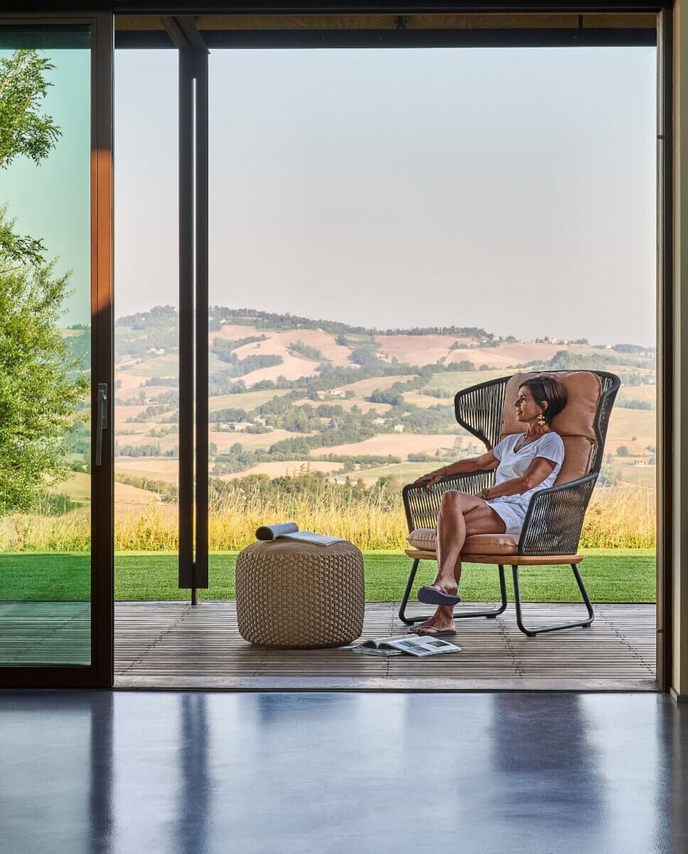 Frau sitzt in hohem, modernen Gartensessel auf der Terrasse