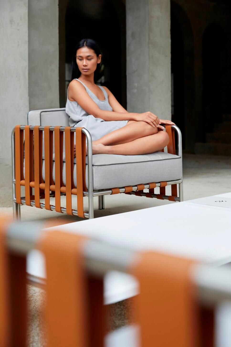 Frau sitzt in modernen Gartensessel auf der Terrasse