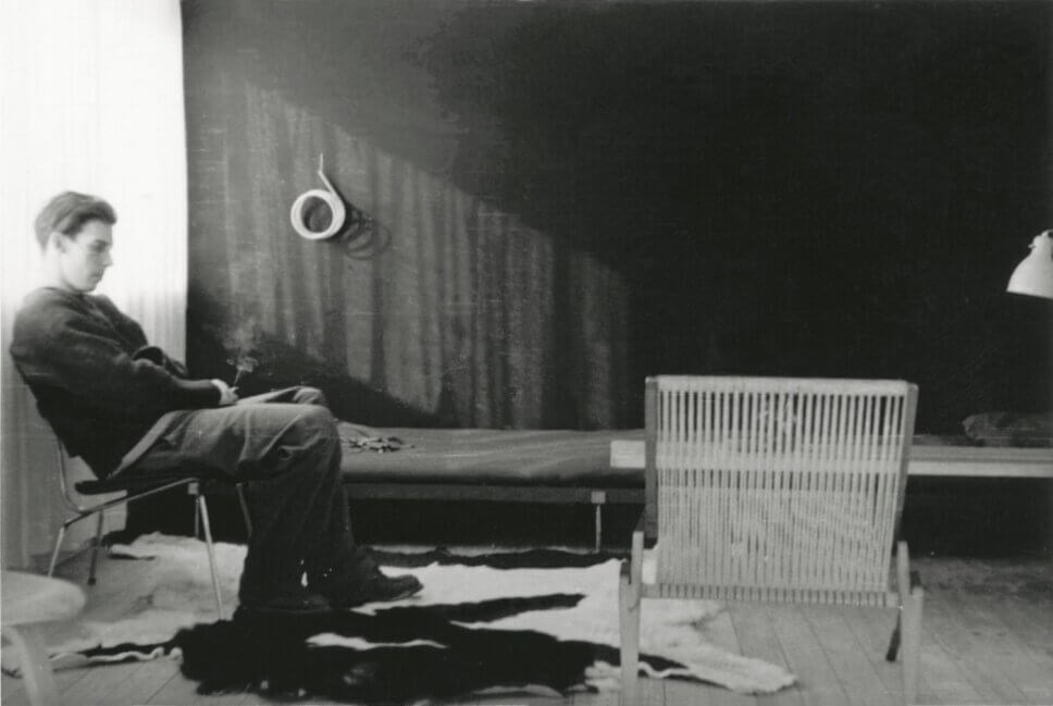 Designer sitzt in den 50er Jahren neben einem Loungesessel, ein skandinavischer Designklassiker