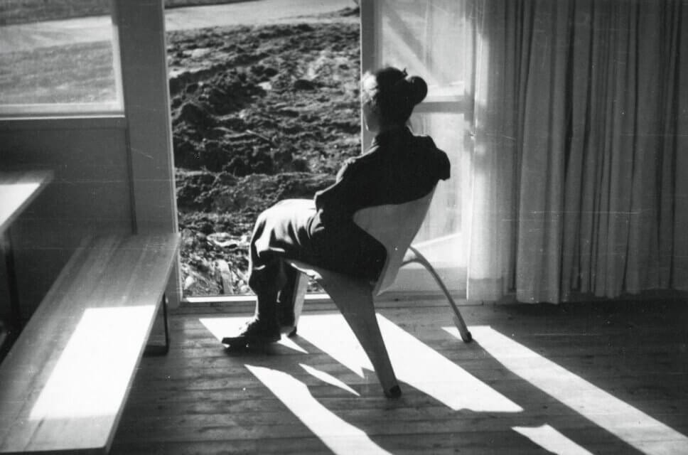 Frau sitzt am Fenster auf skulpturalem Holzstuhl, einem skandinavischen Designklassiker