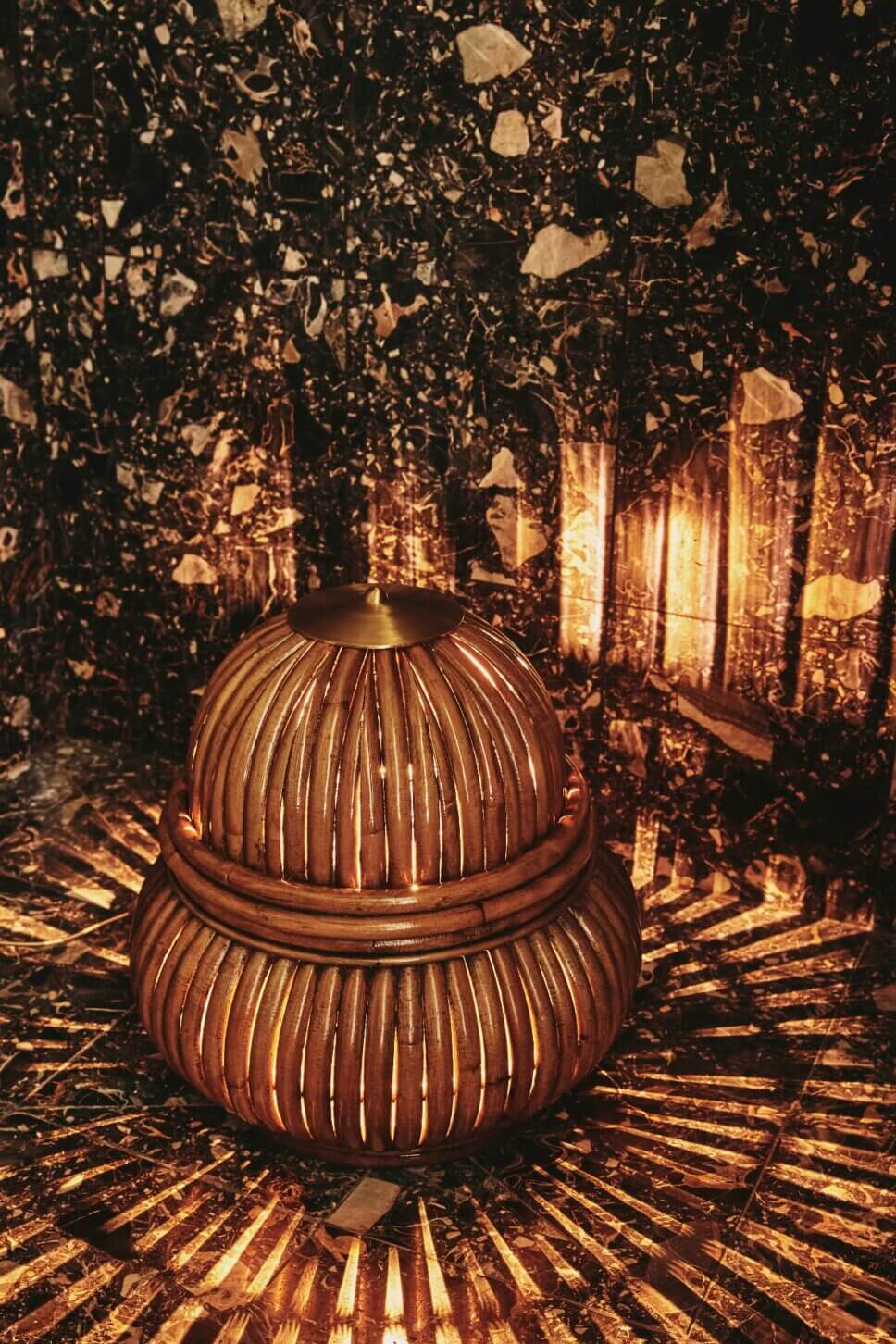 Rattanleuchte zaubert Licht- und Schattenspiel auf den Fußboden im Garten