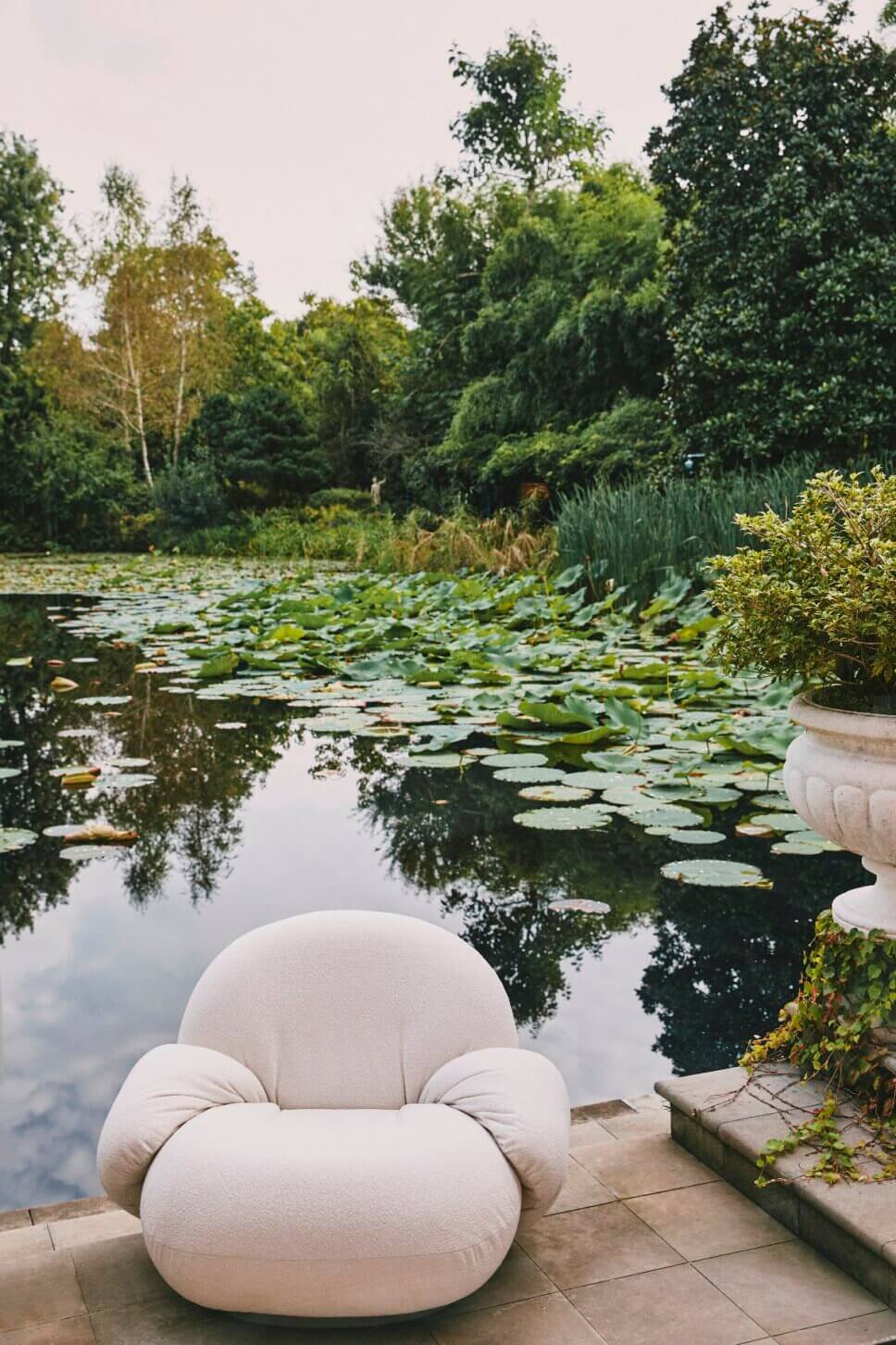 Retro Gartensessel stehen auf der Terrasse vor Gartenteich