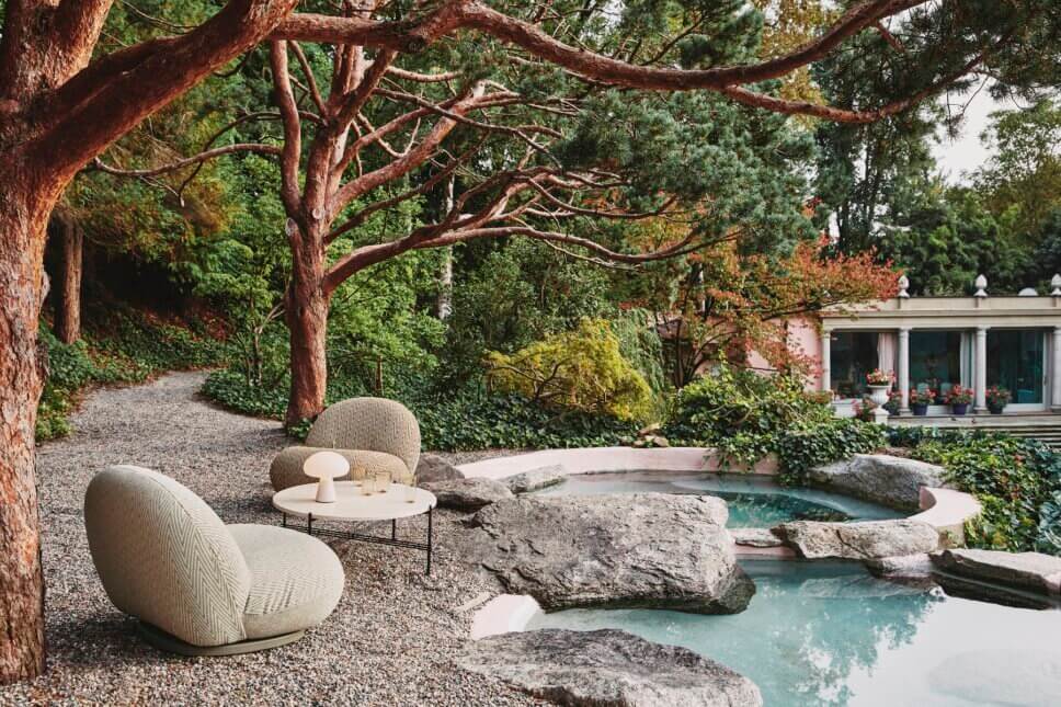 Retro Gartensessel stehen auf der Terrasse vor Gartenteich