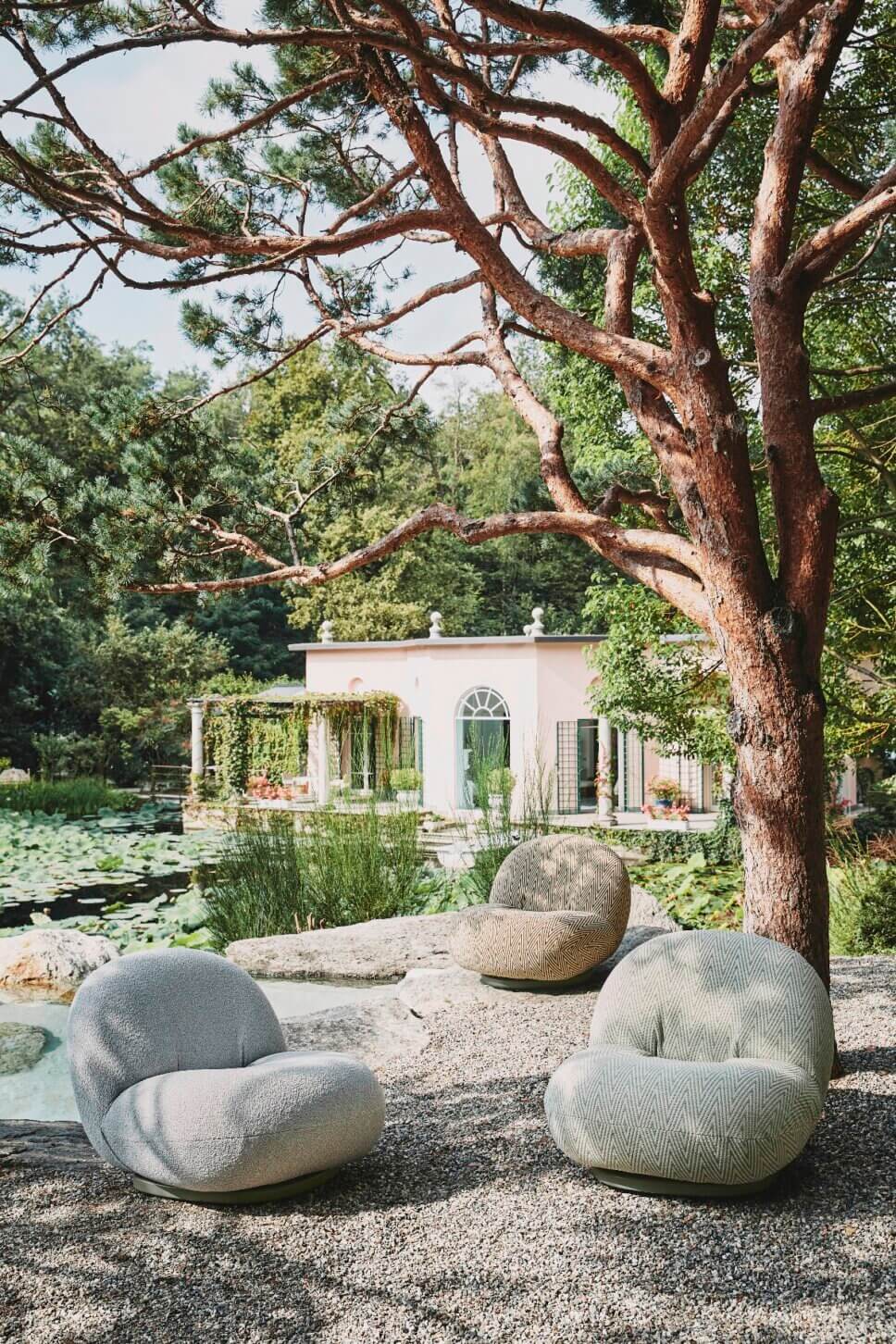 Retro Gartensessel stehen auf der Terrasse vor Gartenteich