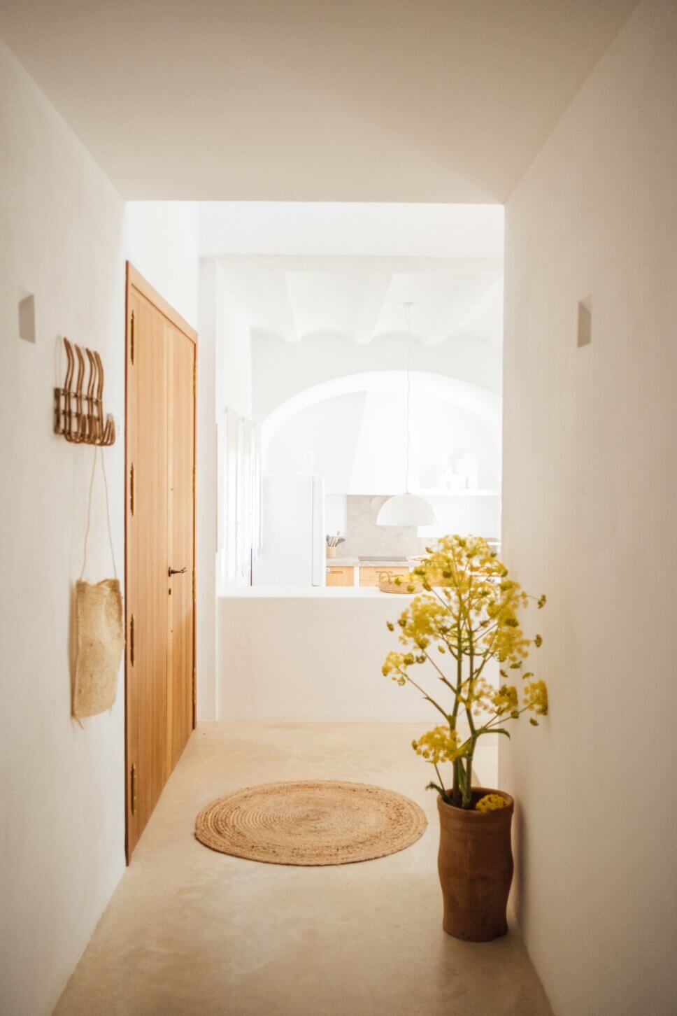 Eingang in moderner spanischer Finca mit Blick in offene Küche und Tonvase im Vordergrund