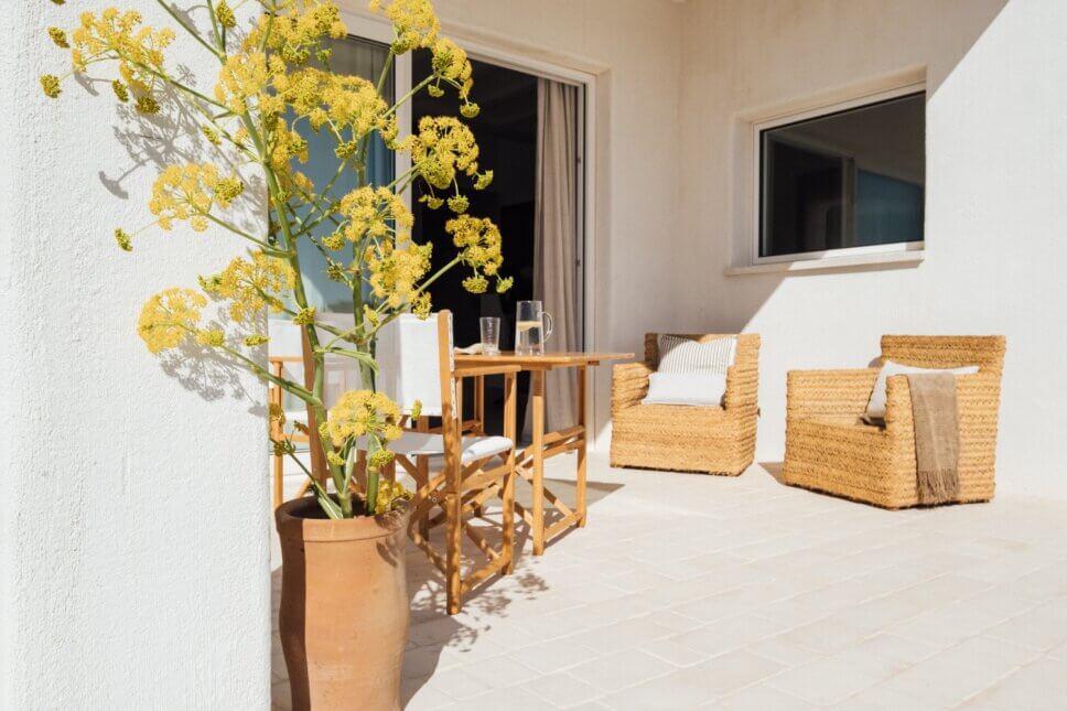 Weiße kleine, mediterrane Villa mit Korbstühlen auf Terrasse