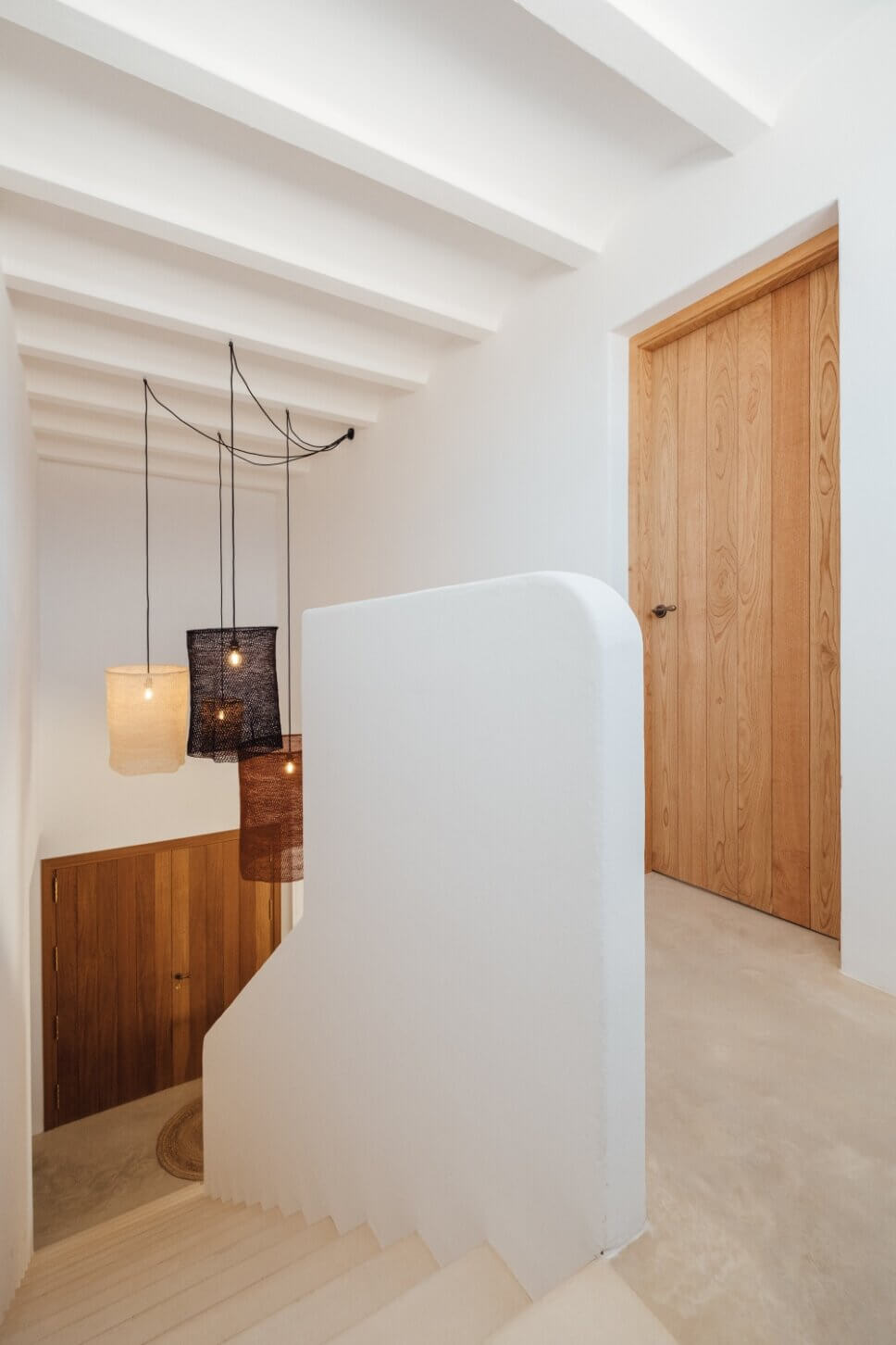 Treppe in moderner spanischer Finca mit Hängelampen aus geflochtenem Seil im Vordergrund