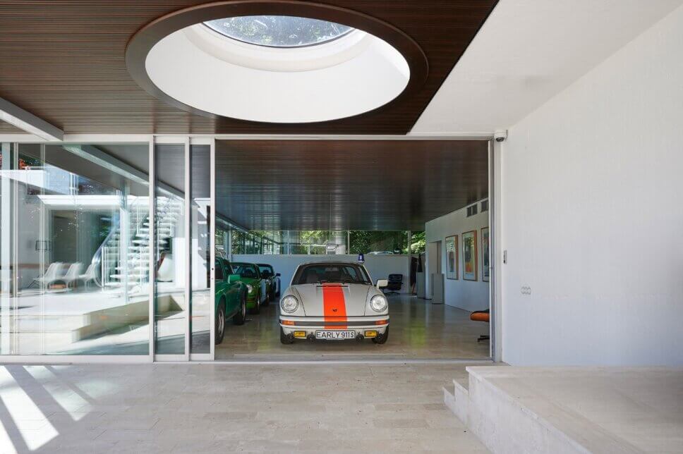 Moderne Villa aus den 60er Jahren mit großer Fensterfront und einem Porsche 911 im Vordergrund