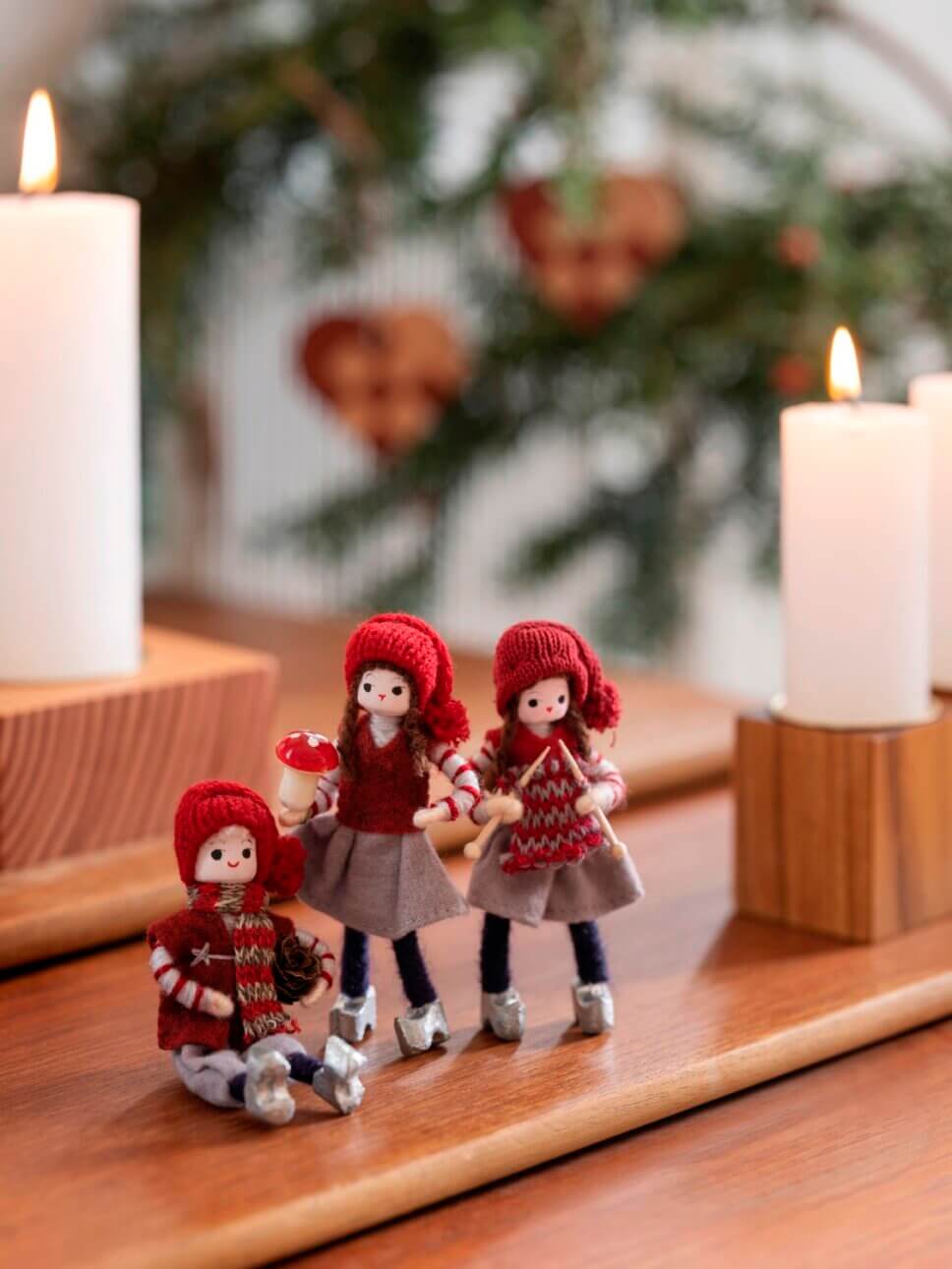 Drei Weihnachtselfen aus Filz mit Strickmützen stehen auf Beistelltisch