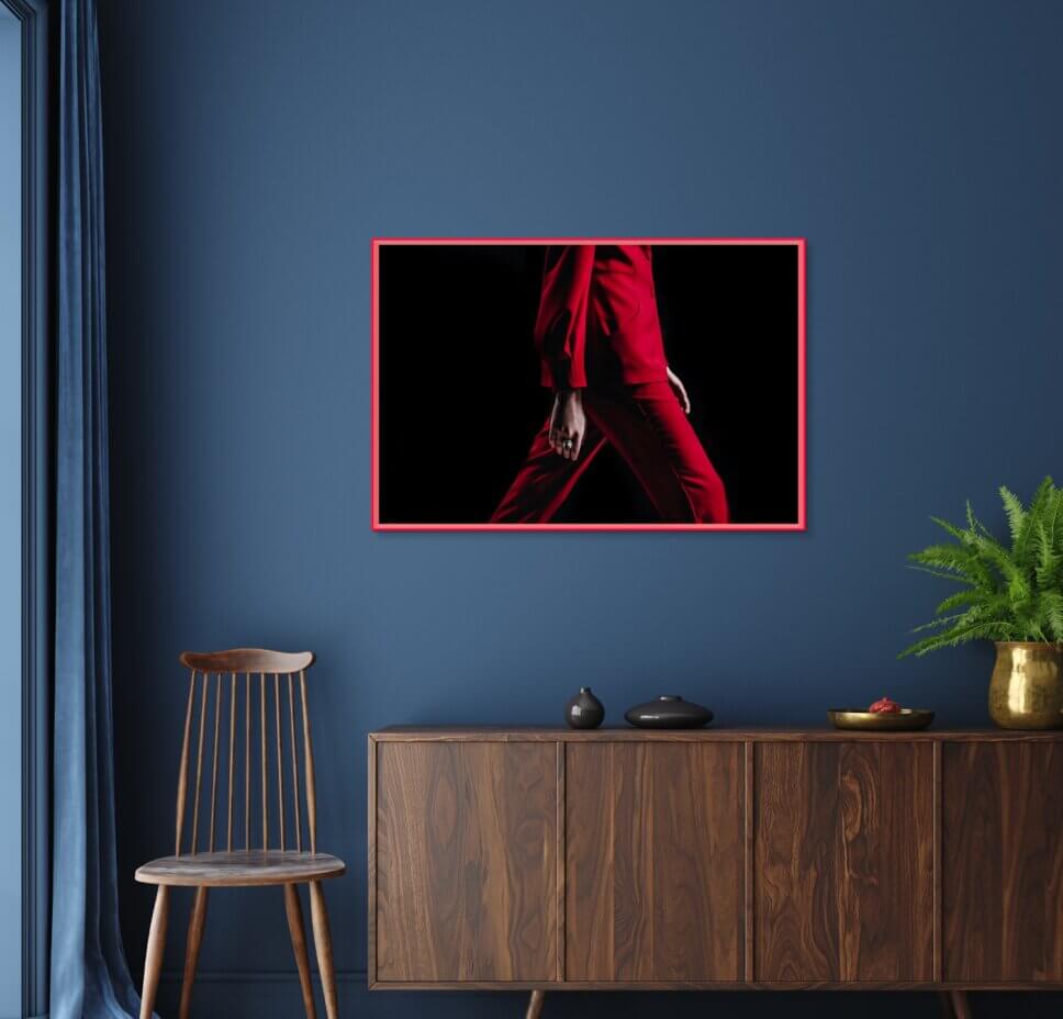 Fotografie in neonrotem Bilderrahmen über Sideboard aus Holz