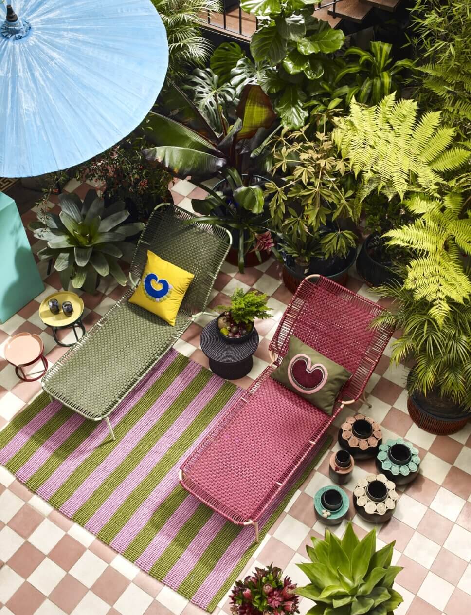 Bunte Liegestühle auf bepflanzter Terrasse